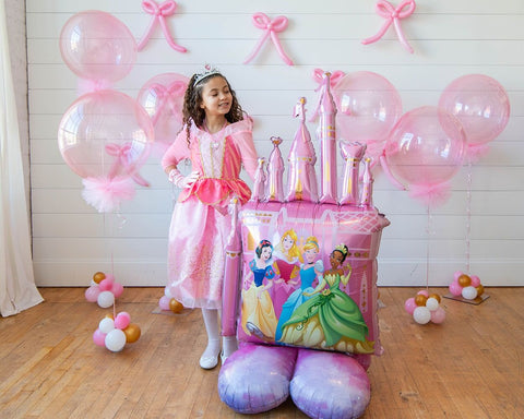 A little girl posing next to the Disney Princess Airloonz mylar balloon castle in Manahawkin NJ, at Party Fair.
