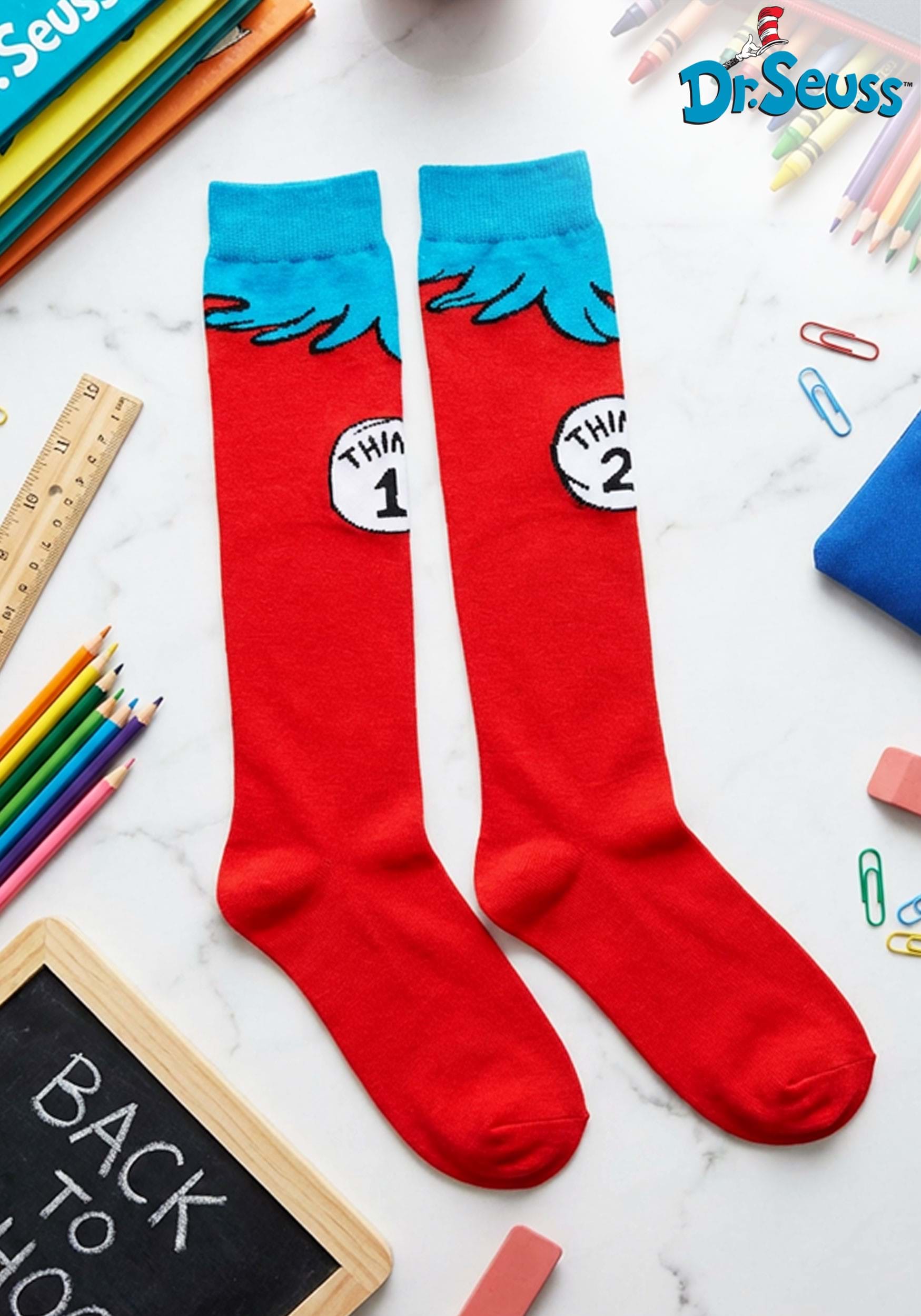 Close-up of Thing 1 & 2 officially licensed kids socks showing knit-in graphics, soft stretch blend, and 17” length. on a white background with stationery items.