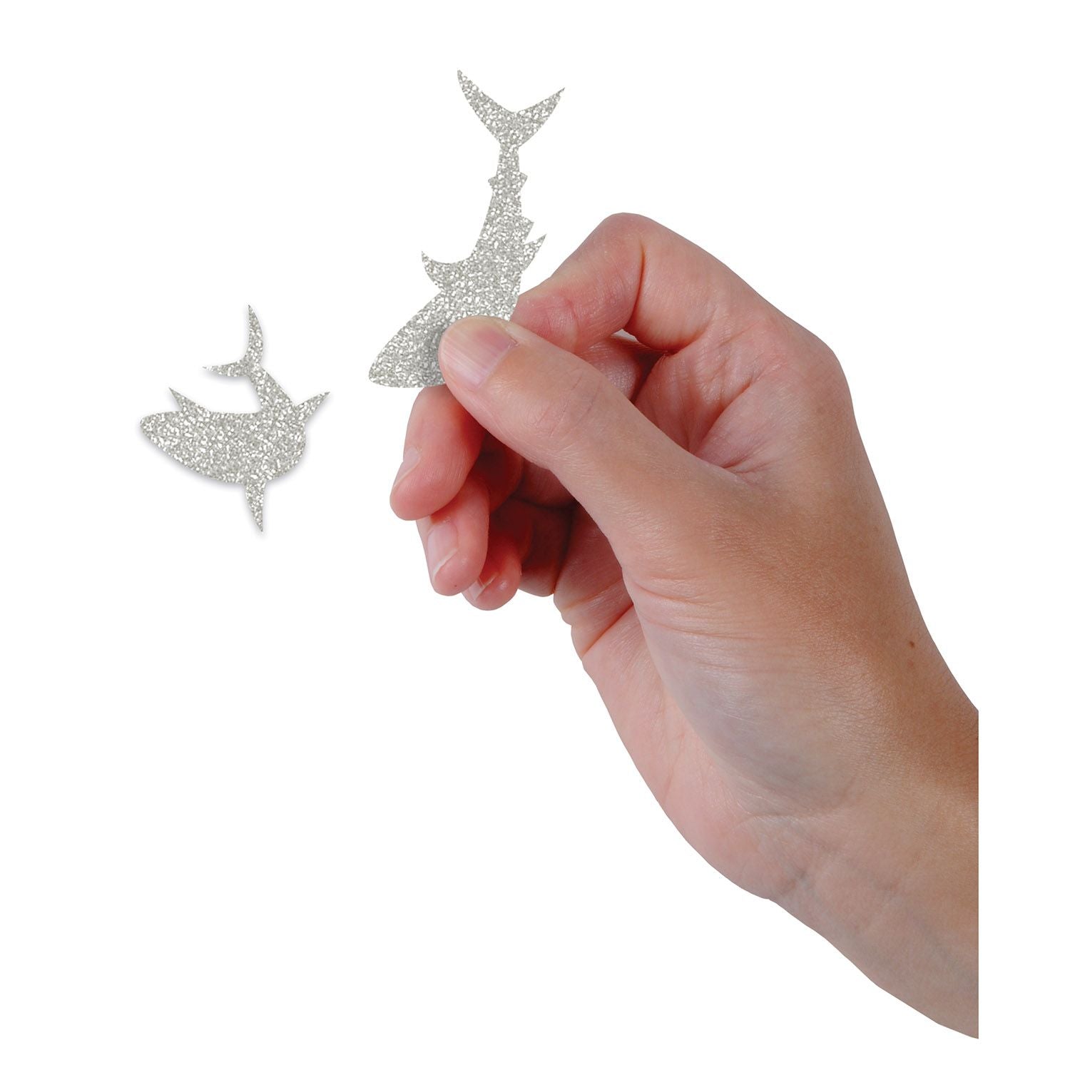 Hand holding a small silver shark Size comparison of large shark confetti pieces for party table décor