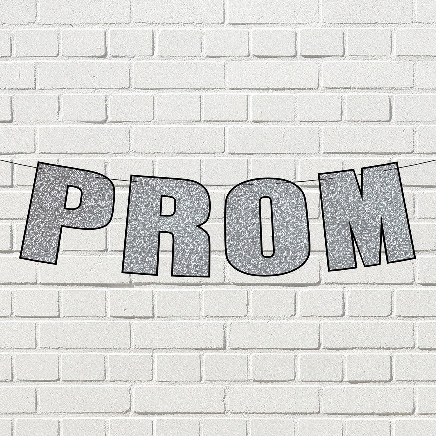 Silver glitter prom streamer banner displayed on a white Brick wall.