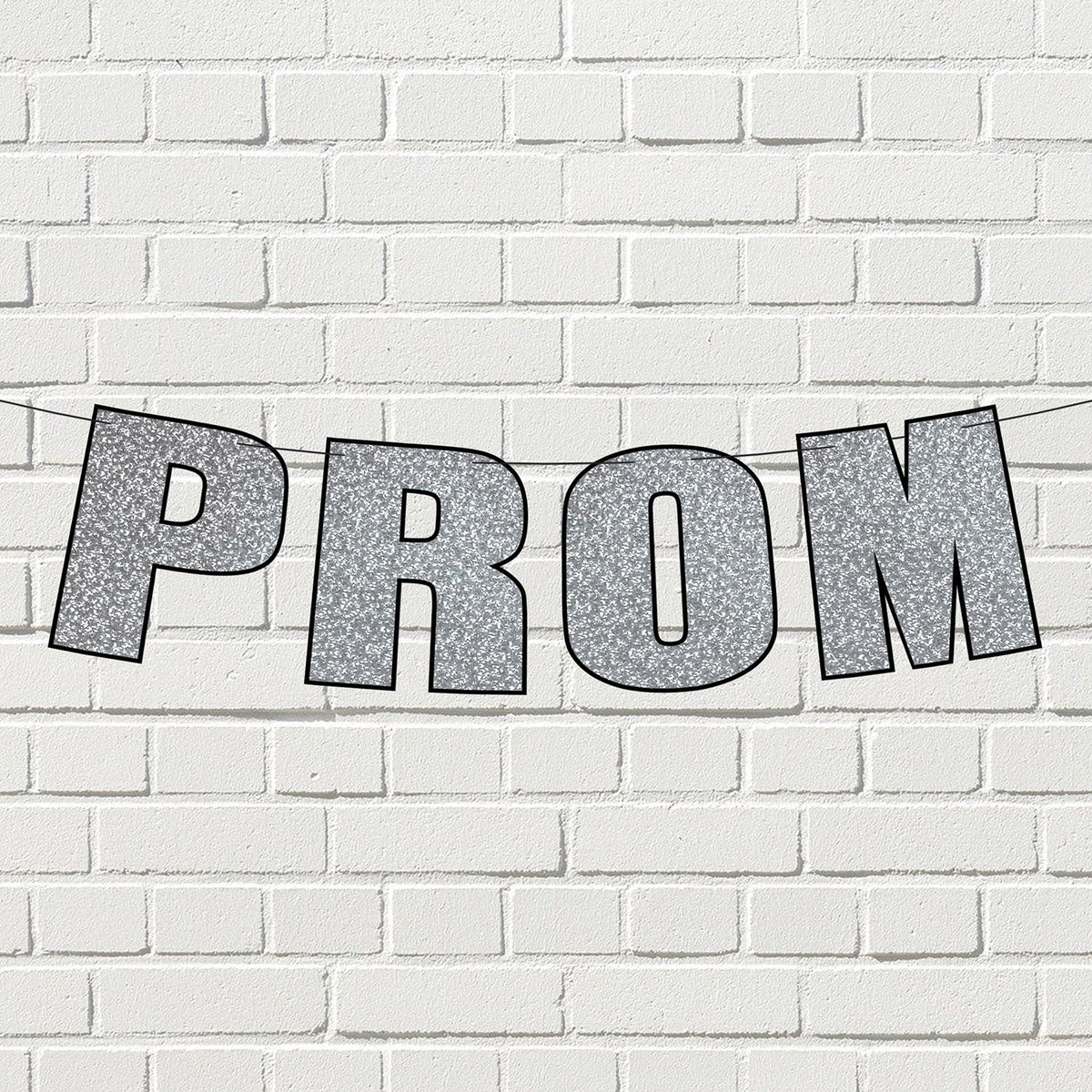 Silver glitter prom streamer banner displayed on a white Brick wall.