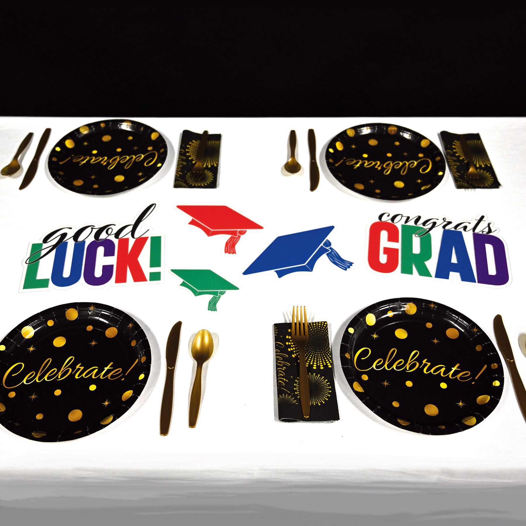 Multicolor Congrats Grad plastic cutouts displayed with Graduation-themed tableware set  on a white background.